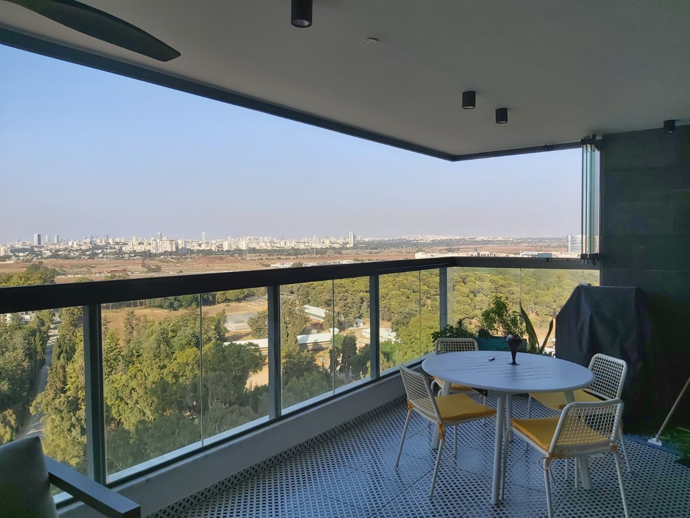 Ağaçlık manzaraya açılan cam balkon oturma alanı