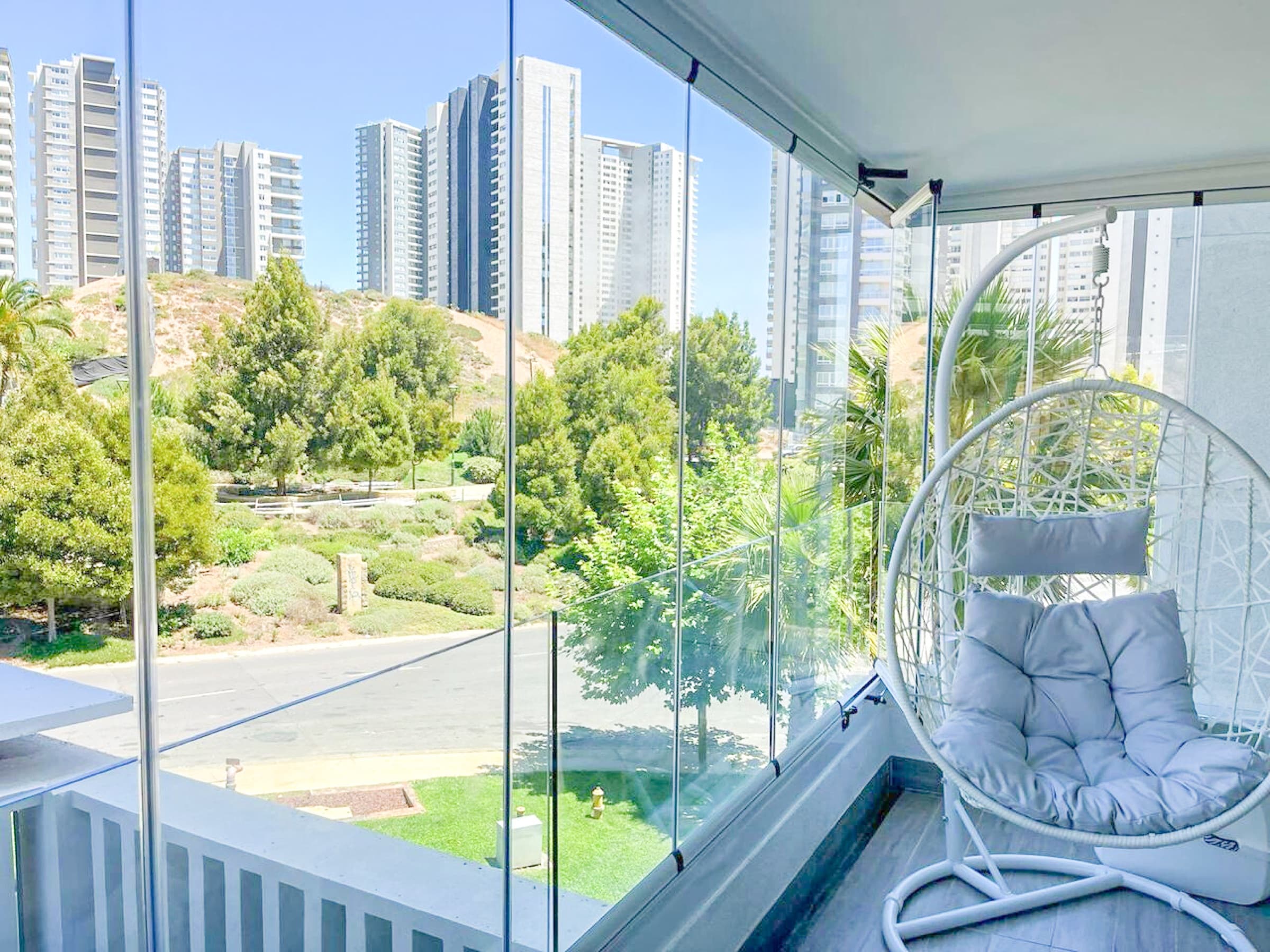Salıncaklı koltuk ve bitkilerle döşenmiş cam balkon